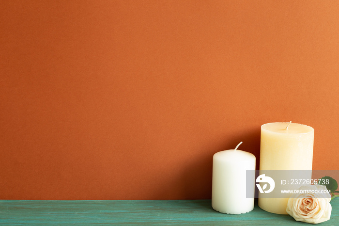 Candles and rose flower on green wooden table. red wall background. Home interior