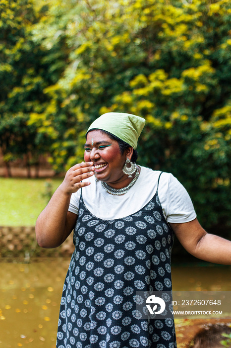 dark skinned Indian non-binary individual smiling in park