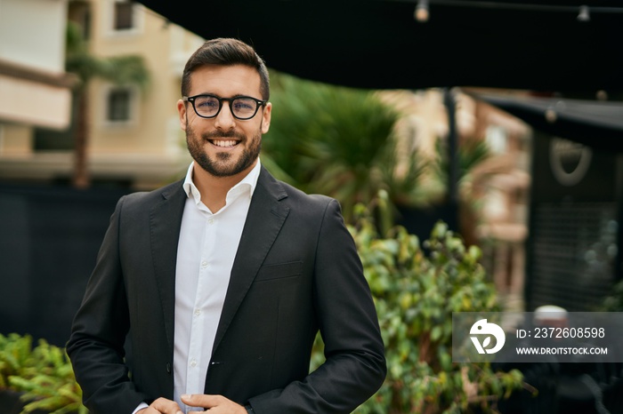 Young hispanic businessman smiling happy standing at the city.