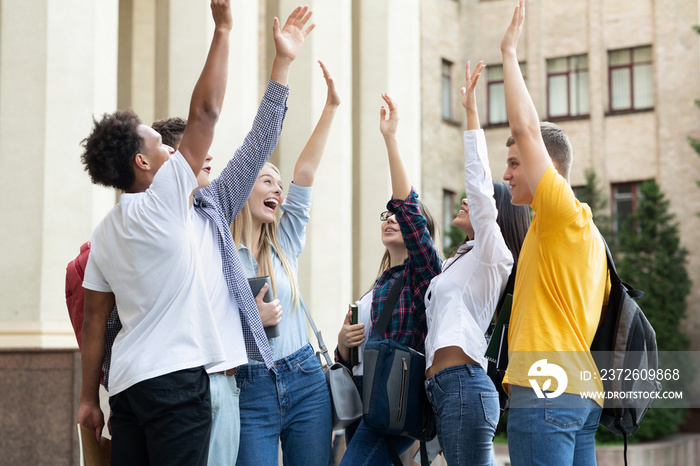 快乐的学生举手站在大学附近