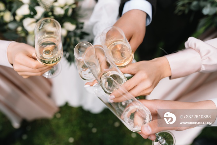Guests at a wedding with the bride and groom clink glasses of champagne or white wine