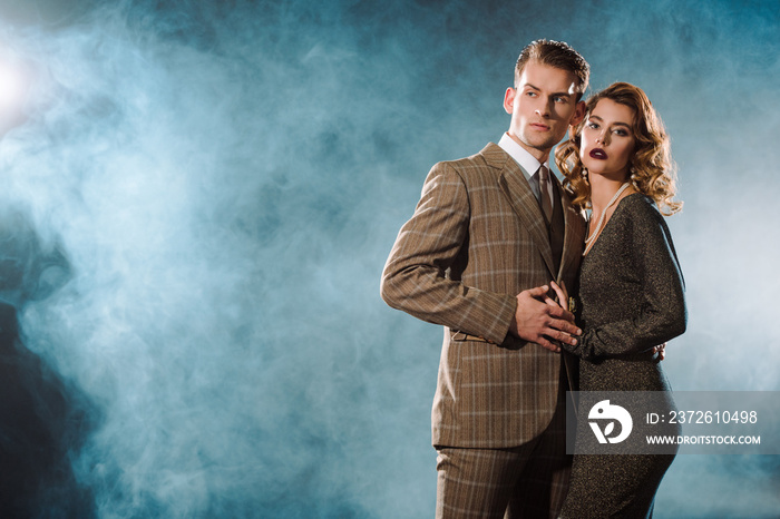 handsome man and beautiful woman in dress standing on black with smoke