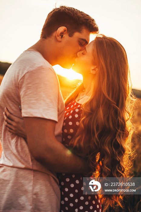 Side view of an caucasian couple kissing in the wheat field. Beautiful summer landscape. Summer vaca