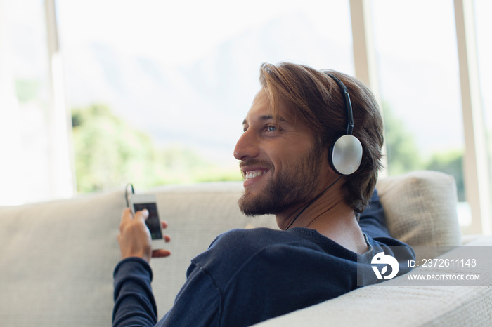 Smiling young man listening to music with headphones and mp3 player