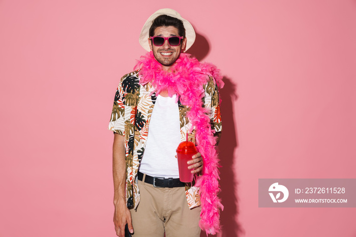 Portrait of cheerful young man wearing boa smiling while drinking soda