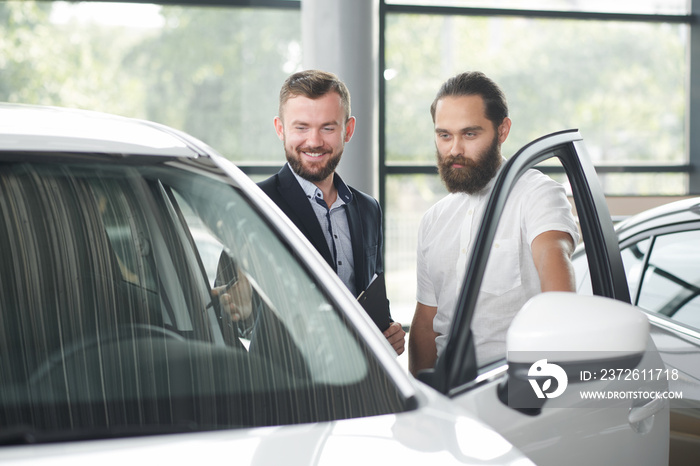 Client of car dealership observing car with manager.