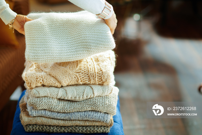 Closeup on elegant woman prepare sweaters pile for storage