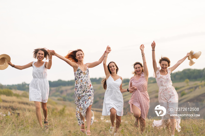 The company of cheerful female friends have a great time together on a picnic in a picturesque place