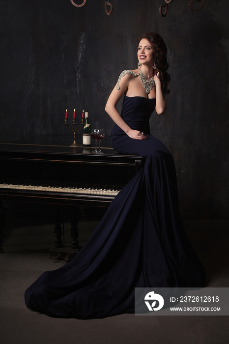 beautiful young woman in black dress next to a piano with candelabra candles and wine, dark dramatic