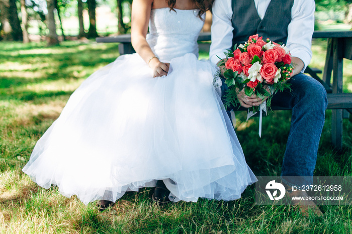 country bride and groom in grass sitting on picnic table