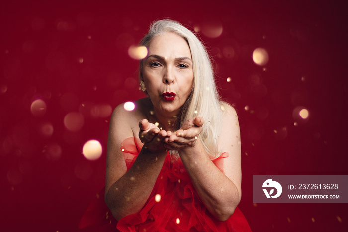 Attractive senior woman blowing glitters