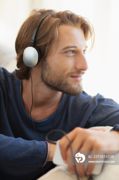 Serene young man listening to music with headphones and mp3 player