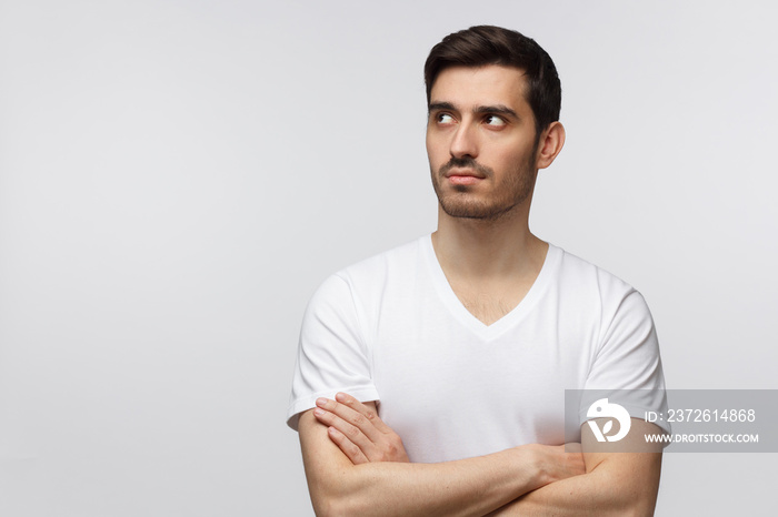 Man standing with folded arms and troubled look, isolated on gray background