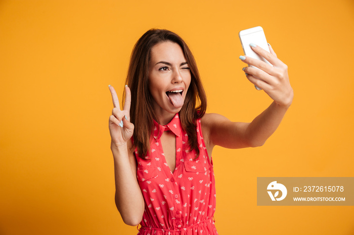 Close-up portrait of young funny brunette woman makes selfie on smartphone