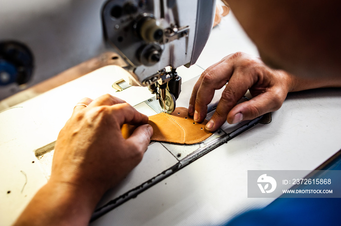 The master sews leather garments at the factory