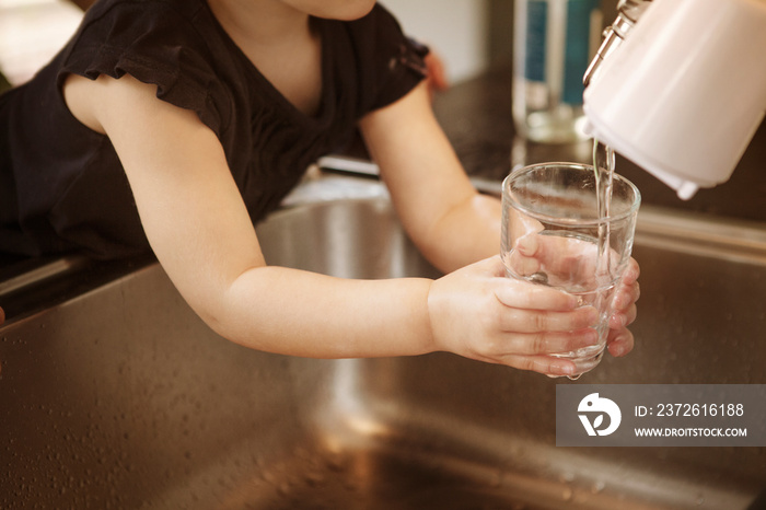 View of girl (2-3) pouring fresh water in glass