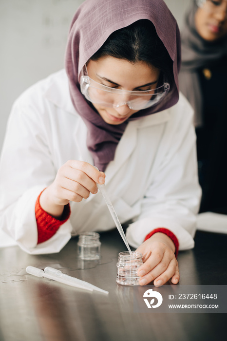 Teenage student wearing hijab studying chemistry in high school