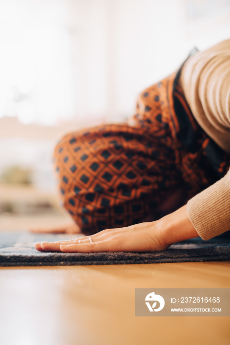 Close-up of woman wearing hijab praying on carpet at home