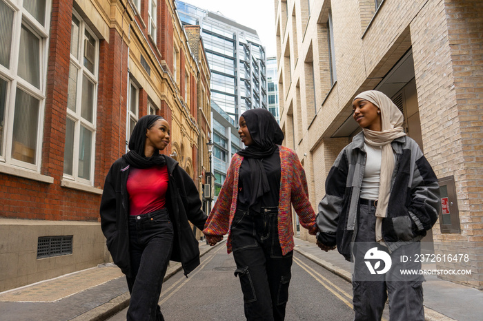 Three young women wearing hijabs walking in city