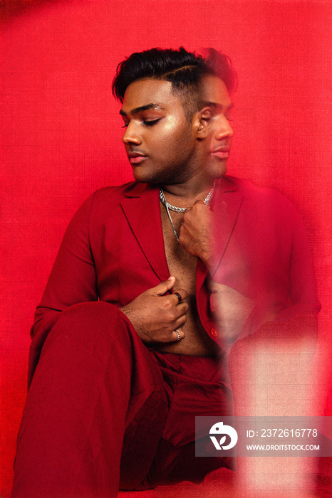 Malaysian Indian individual dressed in red clothing, against a red background, posing and laughing