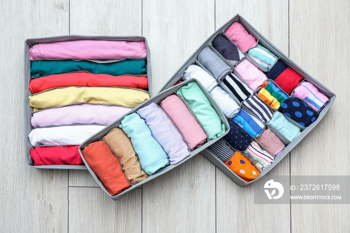 Organizers with clean clothes on wooden floor