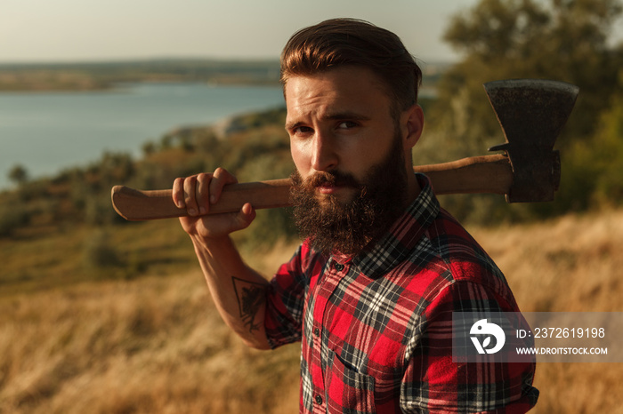 Bearded male with axe in countryside