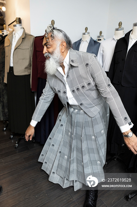 gray hair bearded man in skirt suit smiles and dances in workshop