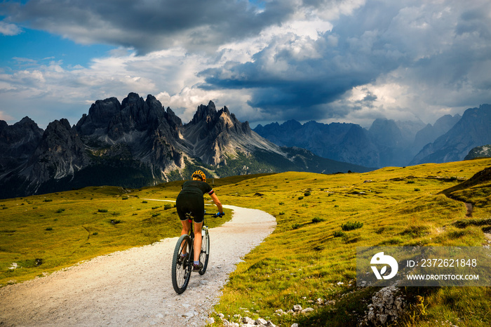 Tourist cycling in Cortina dAmpezzo, stunning rocky mountains on the background. Woman riding MTB e