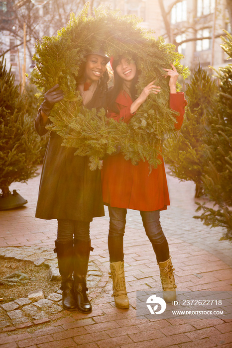 Female friends posing with Christmas wreath