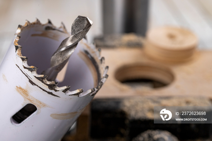 Drilling metal hole saw in a piece of wood. Making holes in a carpentry workshop.