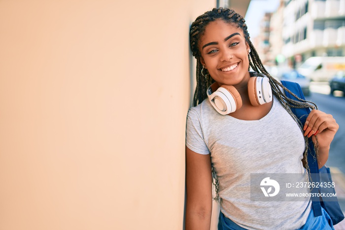 Young african american student woman smiling happy leaning on the wall at the university campus