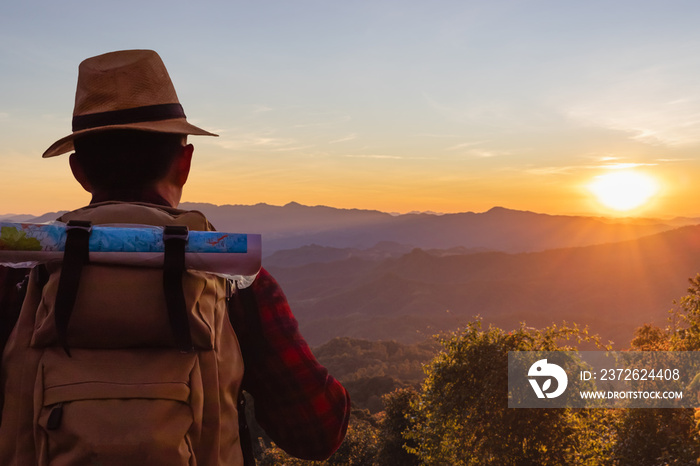 male tourist with backpacks stand to the top of mountain and enjoying sunset.