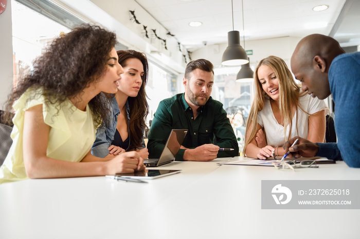 Multi-ethnic group of young people studying together on white desk