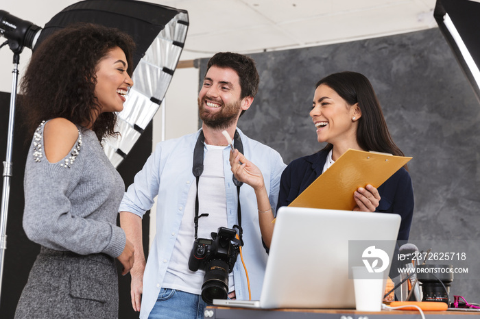 Portrait of happy multiethnic people man and women talking while photographer shooting model in stud