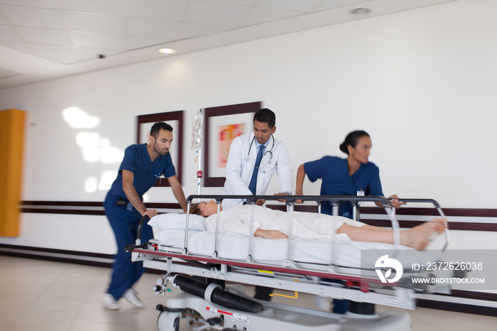 Doctor and nurses rushing patient on stretcher in hospital corridor