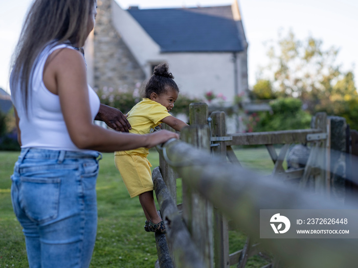 Mother watching son (2-3) climbing fence