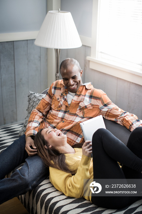 Smiling couple using digital tablet on sofa