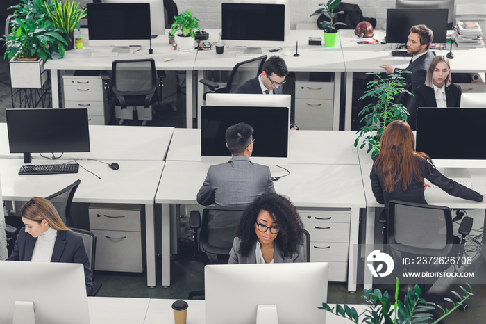 high angle view of professional multiethnic business people working with desktop computers in open s