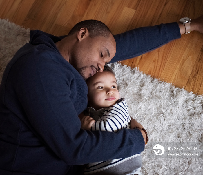 Father and son sleeping on rug at home