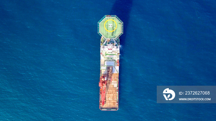 一艘带直升机停机坪和大型起重机的中型红色海上补给船的航拍图像