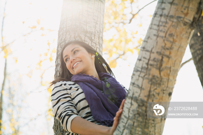 Young woman sitting on tree branch