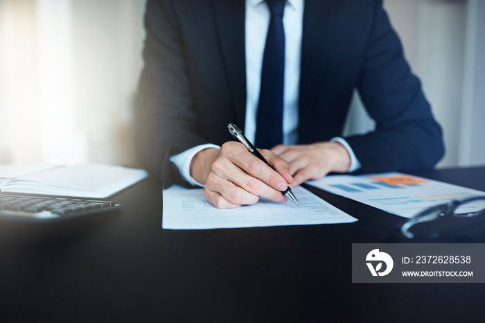 Businessman sitting at his office desk signing documents