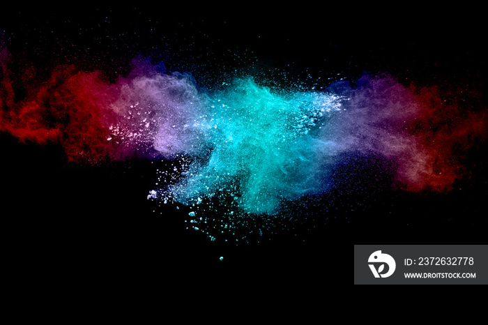 Abstract multicolored powder explosion on black background. Red and blue dust particles splattered o