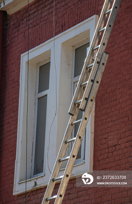 一个延伸梯靠在一栋多户住宅楼的前面，为屋顶做准备