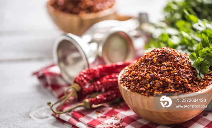 Dried and crushed chili peppers in wooden bowles with parsley herbs