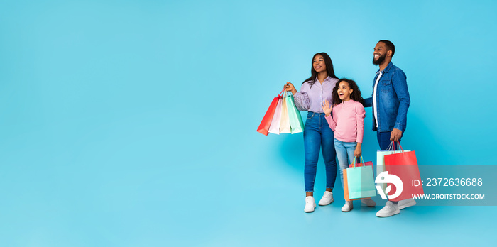 African American cheerful people holding shopping bags looking aside, panorama