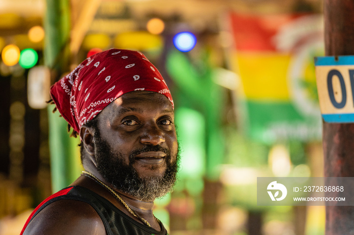 Retrato horizontal de cerca del rostro de un hombre afrocaribeño de barba con un pañuelo rojo en su 