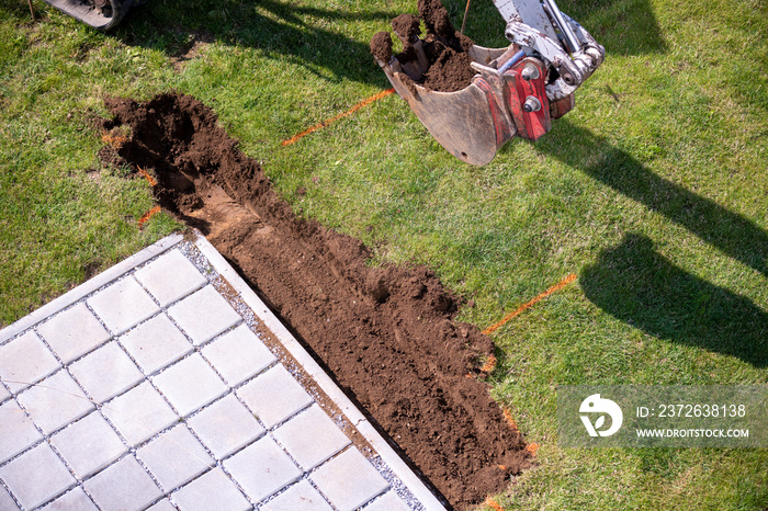 Bagger hebt ein Findament für einen Gartenzaun aus