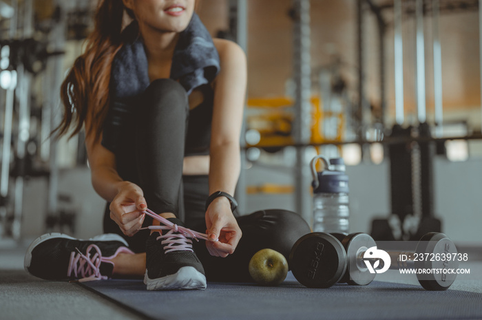 Woman tying shoelaces at gym.young female at gym taking a break from workout..Fitness ,workout, gym 