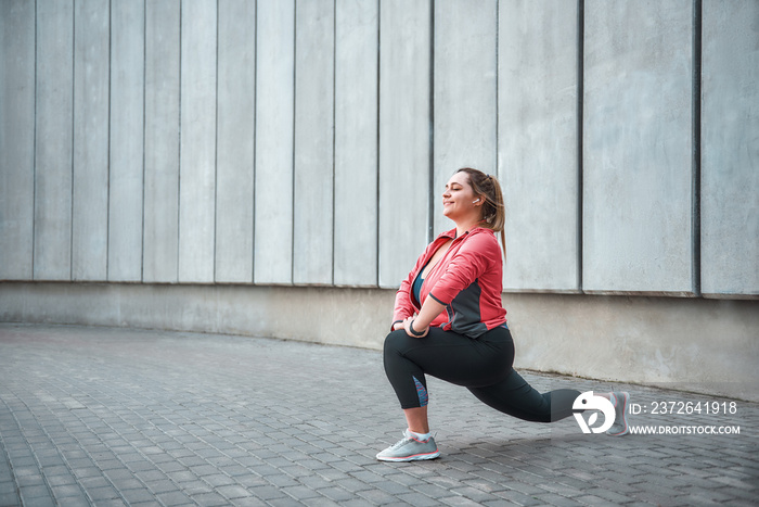 I love sport Happy plus size woman in sport clothes doing stretching exercises and smiling while sta